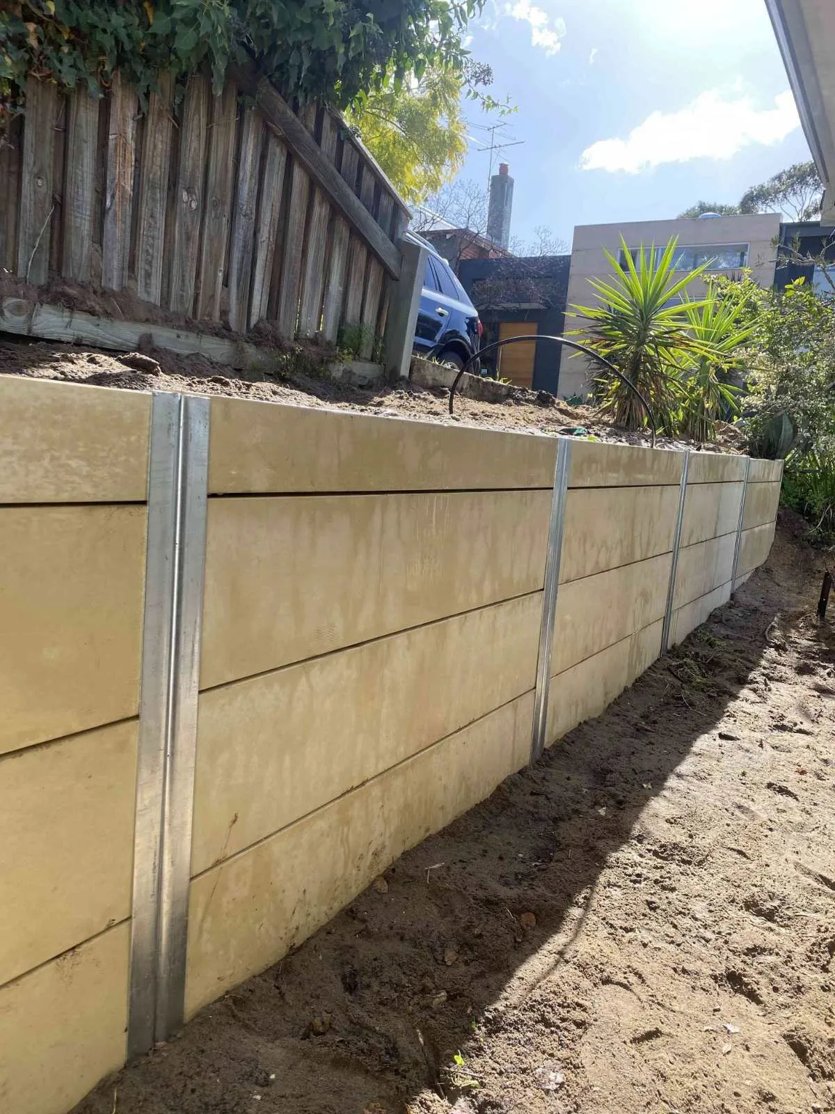Limestone-look panel retaining wall with galvanised steel posts holding back a garden bed in Perth