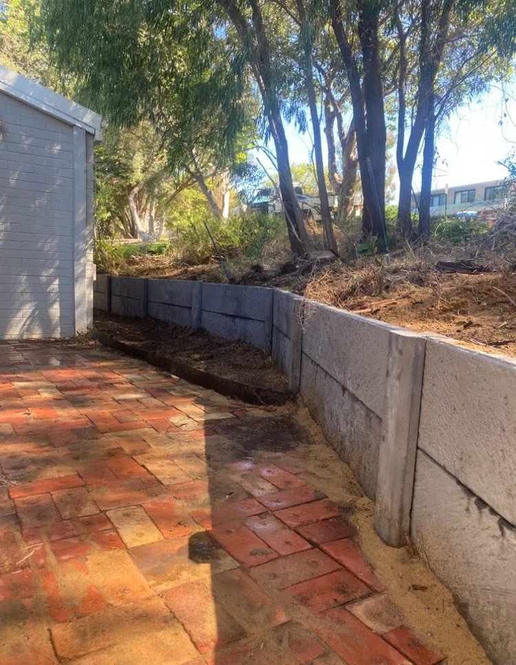 New panel retaining wall along a sloping Perth backyard above a brick paved path
