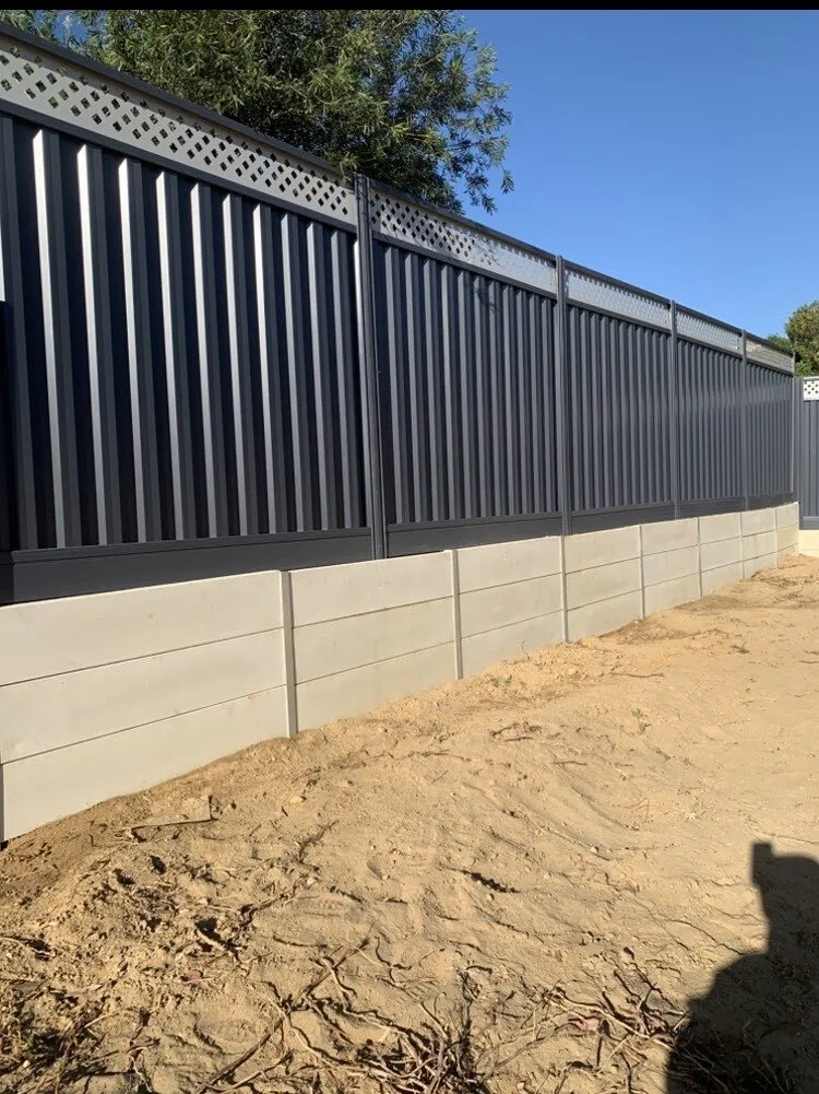 New retaining wall with a dark Colorbond fence built on top, sand backfill still settling, Perth